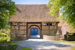Firmeneventlocation 3 Eine gemauerte Scheune mit blauen Türen, perfekt für eine Freie Trauung oder Hochzeit in der Münster-Umgebung, umgeben von viel Grün.