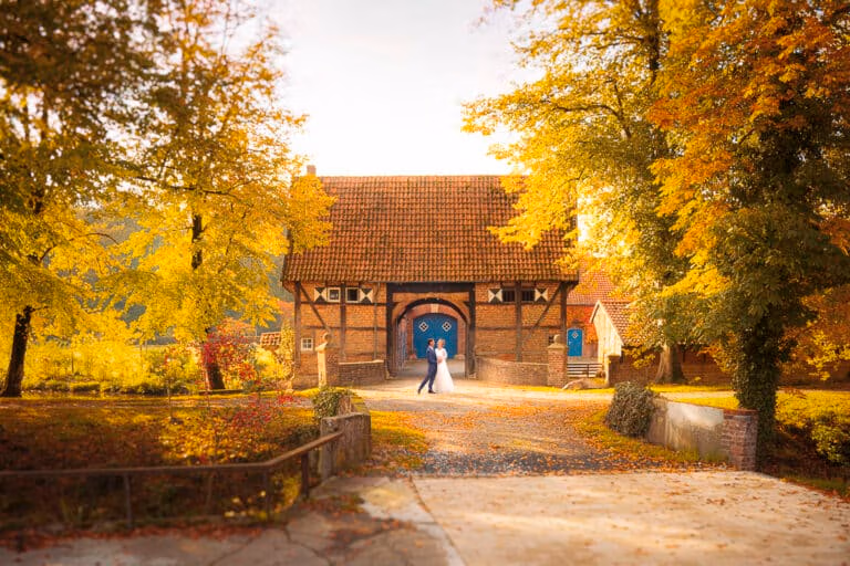 Ein Paar in Hochzeitskleidung steht neben einer rustikalen Scheune, einer atemberaubenden Hochzeitslocation im Herbst.