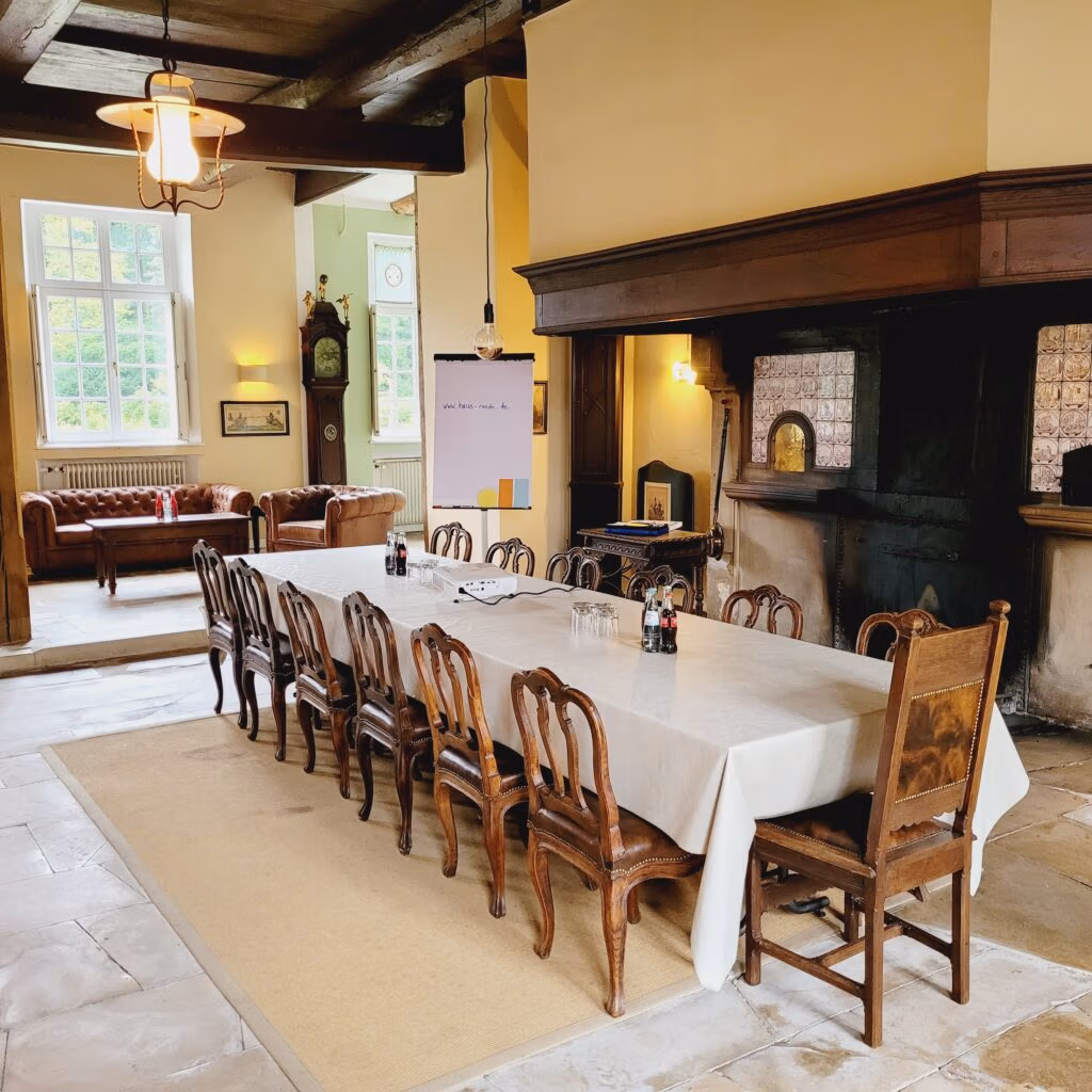 Langer Esstisch mit Holzstühlen in einer großzügigen Münsteraner Hochzeitslocation mit Kamin.