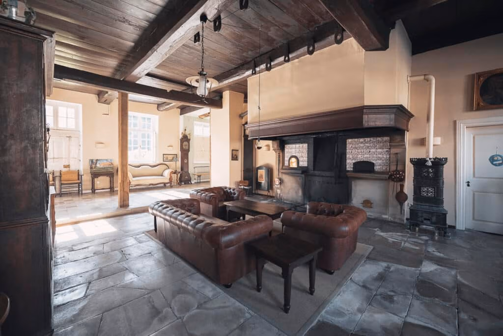 Großzügiges Wohnzimmer mit Ledersofas, Holzbalken und Kamin – ideale Eventlocation Münster.